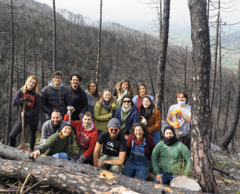 Gabriele Primavera in the center of the picture among a group of other 15 people in a burned forest