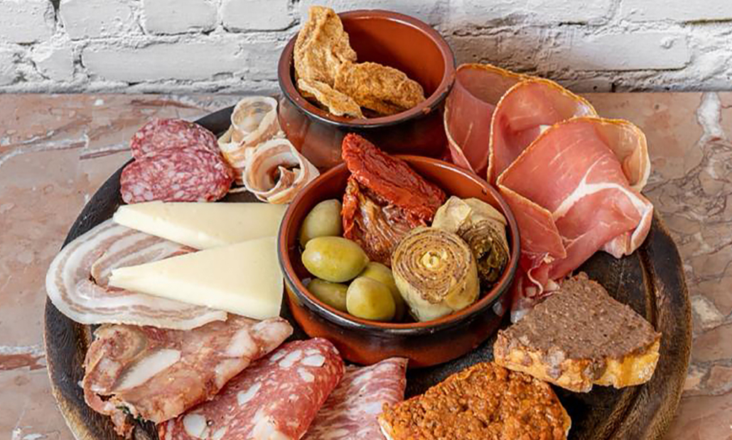 Un tipico tagliere toscano, comprendente vari tipi di salumi, crostini di fegatini, ciccioli e qualche verdura da aperitivo