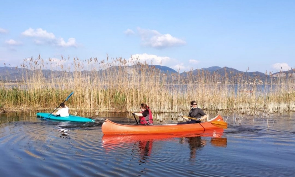 Canoisti sulla laguna del Lago di Massaciuccoli, con sfondo la catena del Monte Pisano